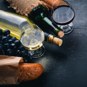 A glass or red wine and white wine with bread and grapes